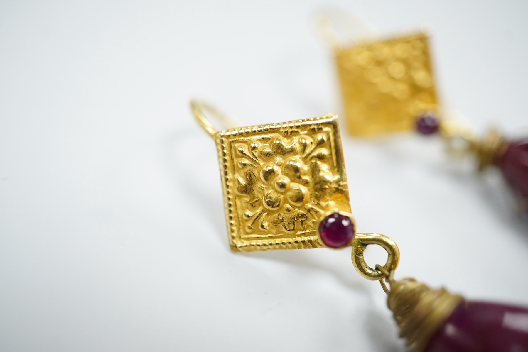 A pair of yellow metal and two stone ruby set teardrop shaped earrings, overall 37mm, gross weight 7.2 grams.